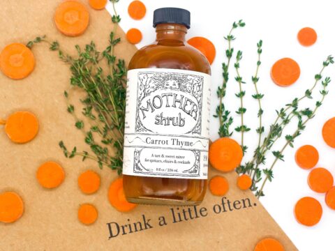 A bottle of Carrot Thyme MOTHER shrub displayed with with carrots and thyme